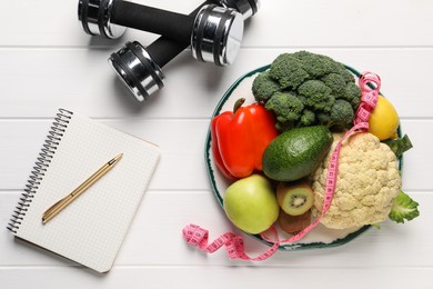 Photo of Healthy diet. Plate with products, measuring tape, dumbbells and notebook on white wooden table, flat lay