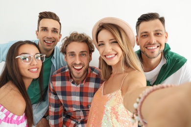 Photo of Group of happy young people taking selfie on white background
