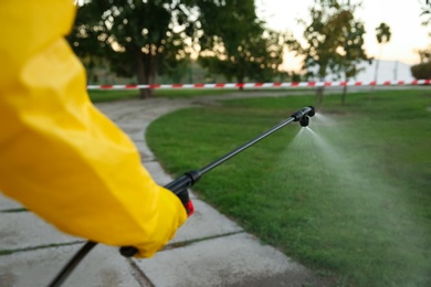 Photo of Person in hazmat suit disinfecting street with sprayer, closeup. Surface treatment during coronavirus pandemic