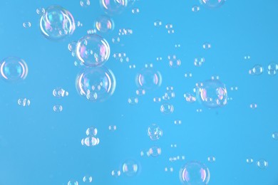 Photo of Beautiful transparent soap bubbles on light blue background