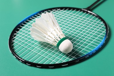 Photo of Feather badminton shuttlecock and racket on green background, closeup