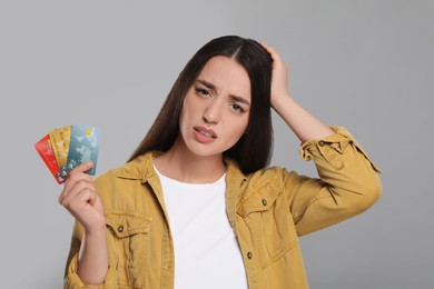 Photo of Worried woman with credit cards on light gray background. Debt problem