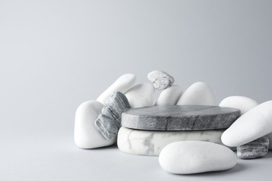 Photo of Presentation for product. Stone podium and pebbles on light grey background. Space for text