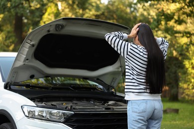 Photo of Young woman standing near broken car outdoors