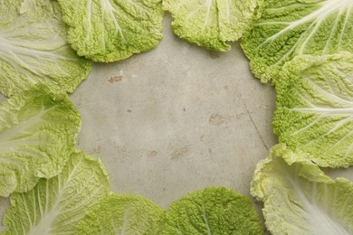 Frame of fresh Chinese cabbage leaves on gray textured table, top view. Space for text