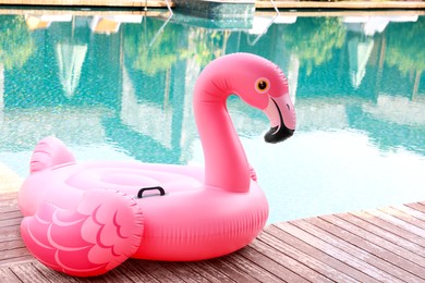 Photo of Float in shape of flamingo on wooden deck near swimming pool at luxury resort