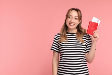 Photo of Happy young woman with passport and ticket on pink background, space for text