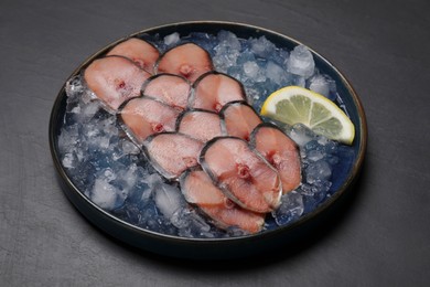 Photo of Raw mackerel slices, ice cubes and lemon on grey table. Fish delicacy
