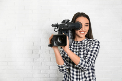 Photo of Operator with professional video camera near white brick wall