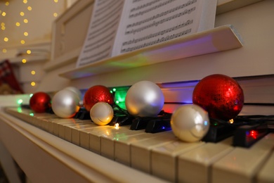 Photo of Festive decor on piano keys indoors, closeup. Christmas music