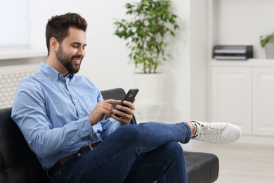 Photo of Handsome young man using smartphone in office