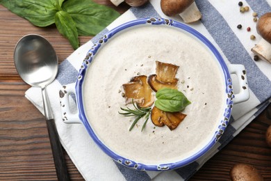 Photo of Delicious homemade mushroom soup served on wooden table, flat lay