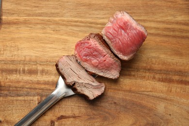 Photo of Delicious sliced beef tenderloin with different degrees of doneness on wooden table, top view