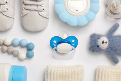 Photo of Flat lay composition with pacifiers and other baby stuff on white background