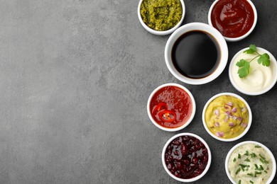 Photo of Different tasty sauces in bowls on grey table, flat lay. Space for text