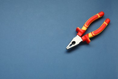 Photo of Combination pliers on blue background, top view. Space for text