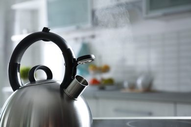 Photo of Modern kettle with whistle in kitchen, space for text