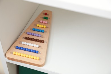 Photo of Wooden board with color bead lines on shelf, space for text. Montessori toy