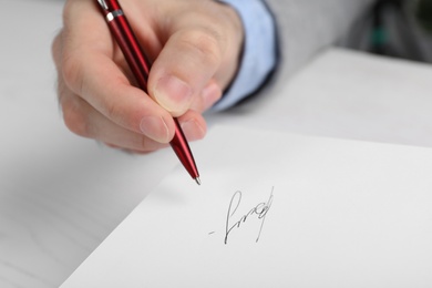 Photo of Writer signing autograph in book at table, closeup