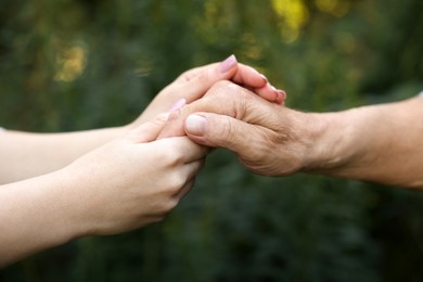 Photo of Trust and support. People joining hands outdoors, closeup