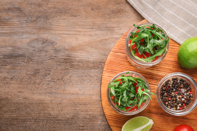 Photo of Healthy salad in glass jars on wooden table, flat lay. Space for text