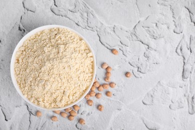 Photo of Chickpea flour in bowl and seeds on light grey textured table, top view. Space for text