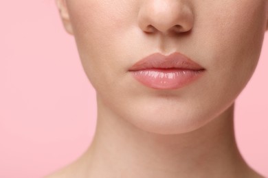 Photo of Woman wearing beautiful lip gloss on pink background, closeup