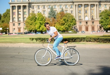 Photo of Handsome young hipster man riding bicycle outdoors