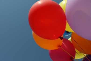 Photo of Bunch of colorful balloons against blue sky, closeup. Space for text