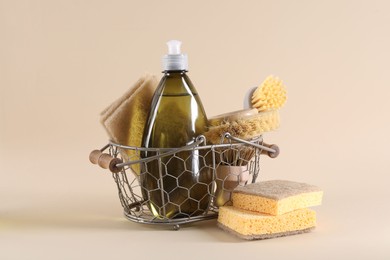 Photo of Bottle of cleaning product, sponges and brushes on beige background