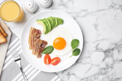 Photo of Tasty breakfast with fried egg, bacon and avocado served on white marble table, flat lay