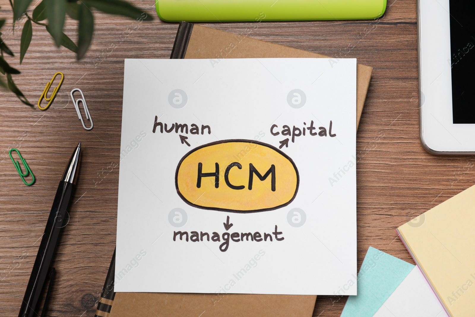 Photo of Paper with HCM abbreviation on wooden office table, flat lay. Human Capital Management