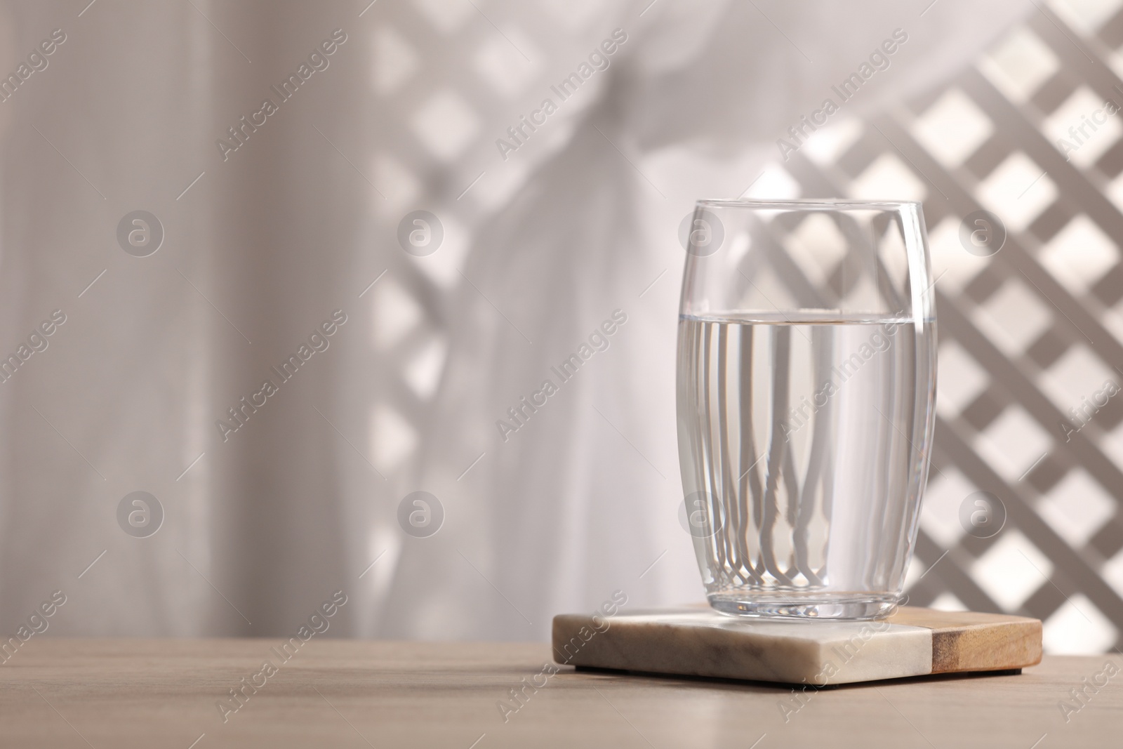 Photo of Glass of pure water on wooden table against blurred background, space for text