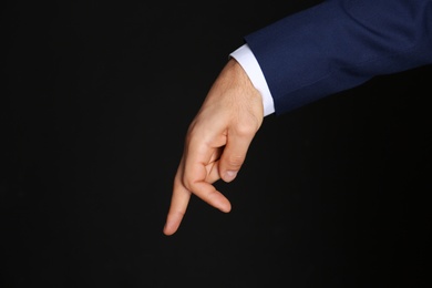 Photo of Businessman imitating walk with hand on black background, closeup. Finger gesture