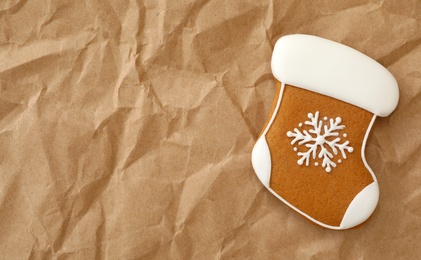 Photo of Christmas stocking shaped gingerbread cookie on crumpled parchment, top view. Space for text