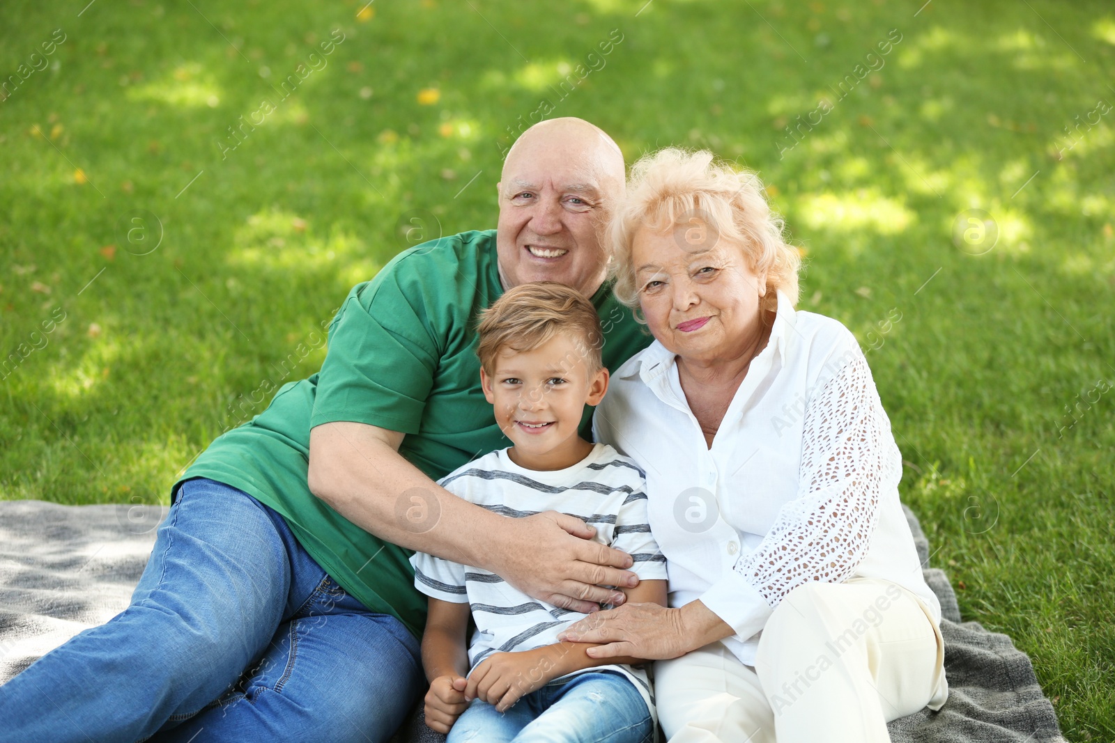 Photo of Happy elderly couple with grandson in park