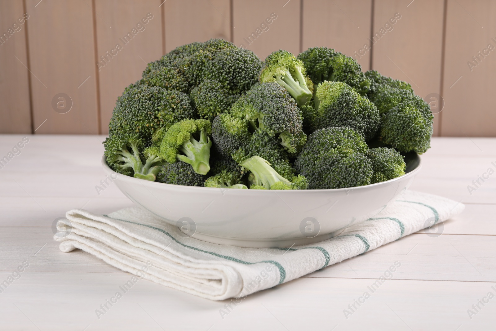 Photo of Bowl of fresh raw broccoli on white wooden table