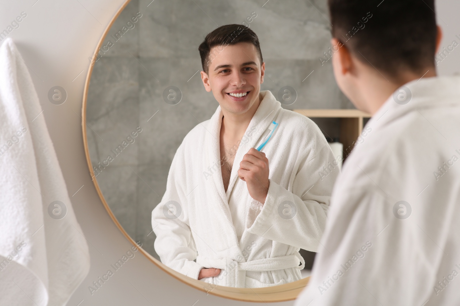 Photo of Happy man with toothbrush near mirror in bathroom