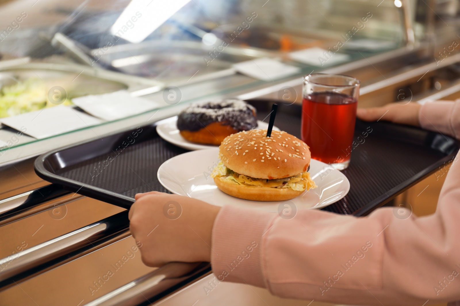 Photo of Little girl with plastic tray near serving line in canteen, closeup. School food