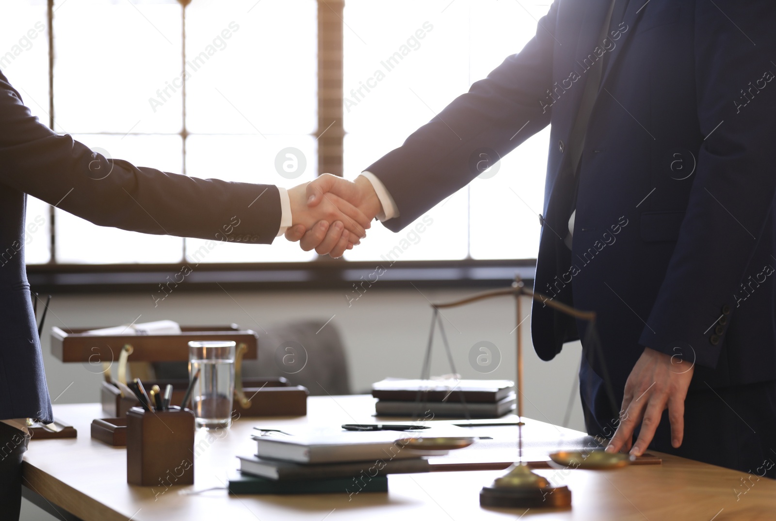 Photo of Male lawyer shaking hands with client in office, closeup