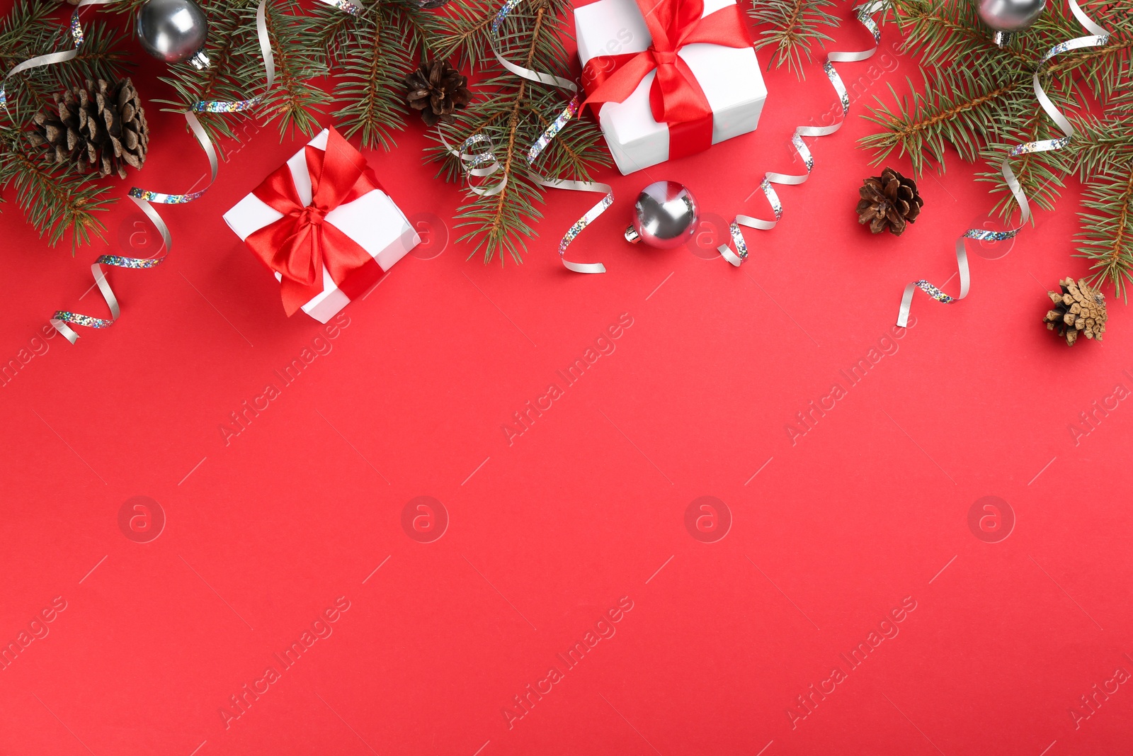 Photo of Flat lay composition with serpentine streamers and Christmas decor on red background. Space for text