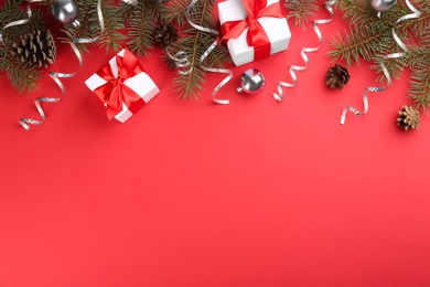 Photo of Flat lay composition with serpentine streamers and Christmas decor on red background. Space for text