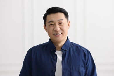 Portrait of smiling businessman near white wall indoors