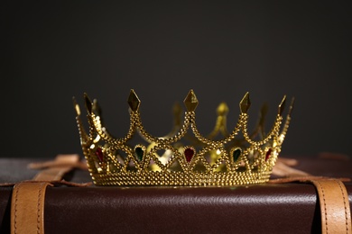 Photo of Beautiful golden crown on suitcase against black background. Fantasy item