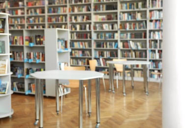 Photo of Blurred view of bookshelves and tables in library