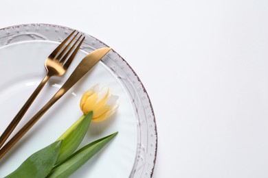 Photo of Stylish table setting with cutlery and flowers on white background, flat lay. Space for text