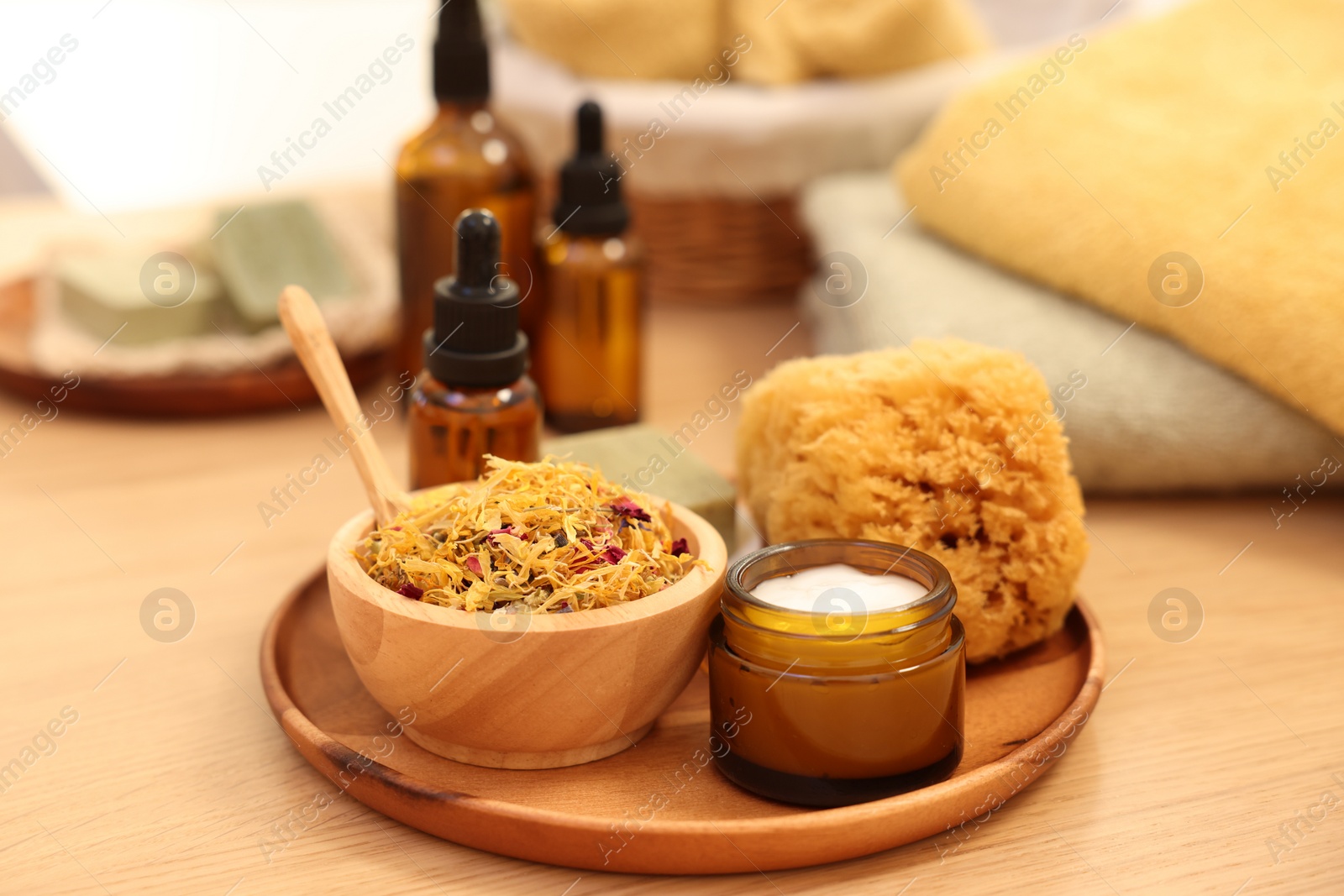 Photo of Dry flowers, loofah and jar with cream on wooden table. Spa time