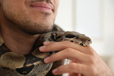 Man with his boa constrictor at home, closeup. Exotic pet
