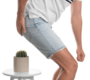 Photo of Man sitting down on cactus against white background, closeup. Hemorrhoid concept