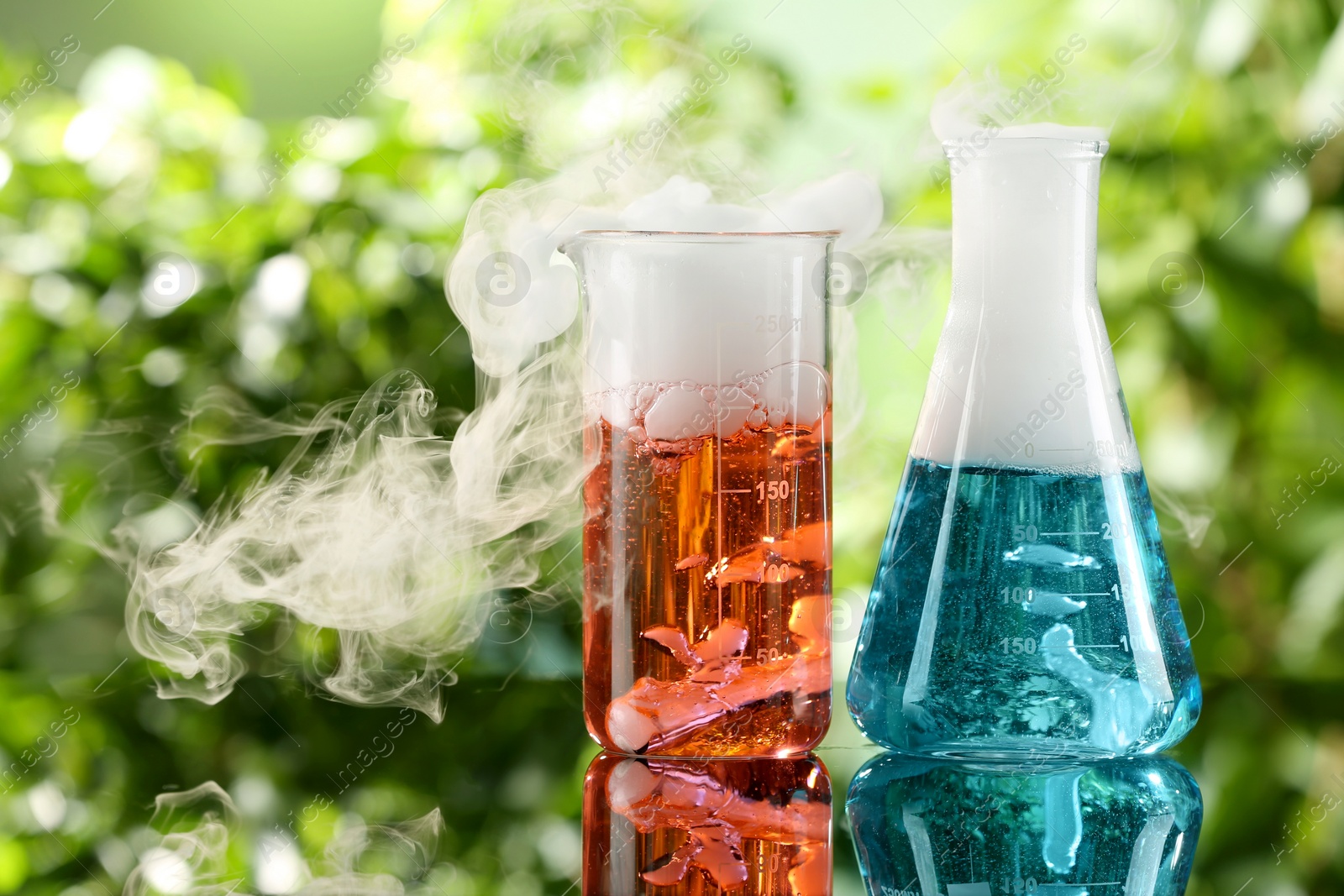 Photo of Laboratory glassware with colorful liquids on glass table outdoors. Chemical reaction